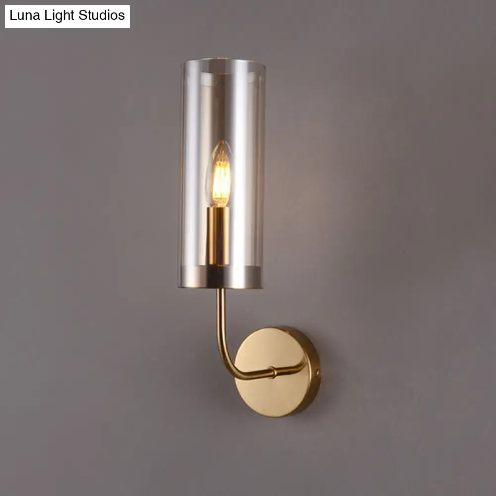 Modern wall mount lamp with brushed brass finish cylindrical glass enclosure and exposed filament bulb for living room
