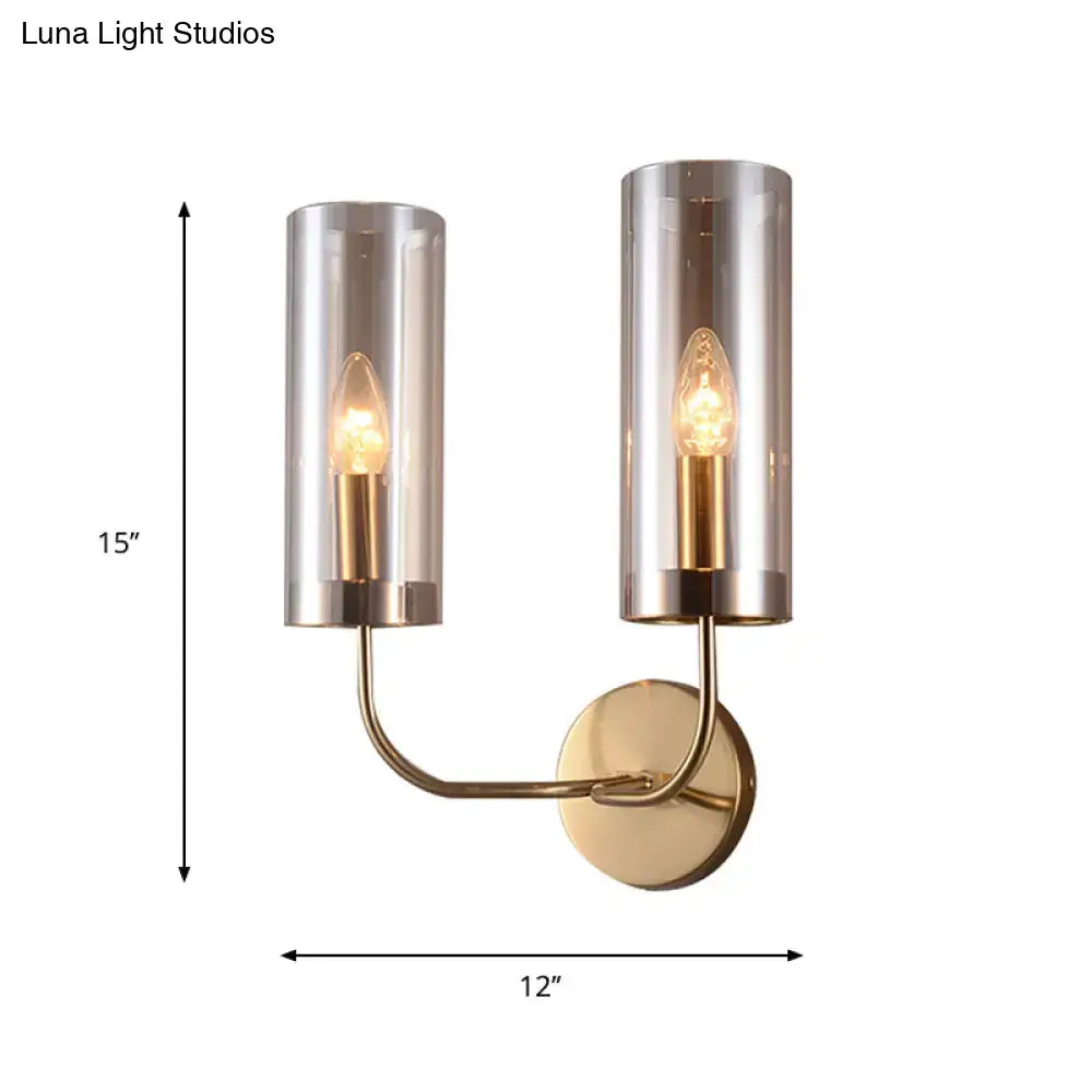 Retro brass wall mount lamp with two gold-toned cylindrical smoked glass shades and exposed filament bulbs for living room