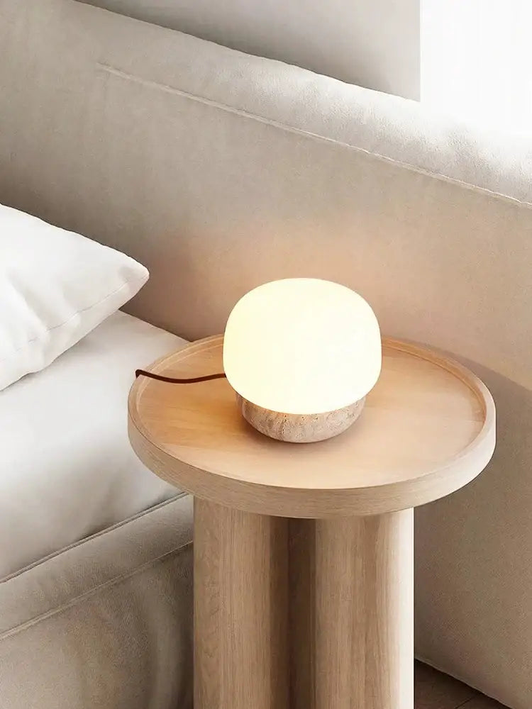 Warm softly glowing decorbites cream mushroom table lamp with textured stone base on minimalist wooden side table