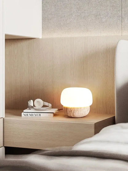 A warm cream mushroom table lamp with a smooth white glass top and textured stone base by decorbites