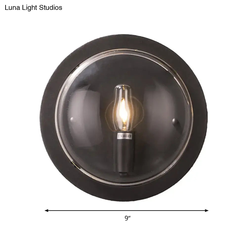 Retro dark gray metal wall sconce featuring a clear glass shade with an exposed edison-style bulb for living room use