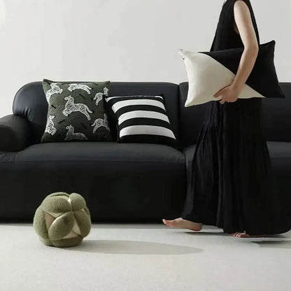 Olive green plush spherical ottoman with stitched geometric panels complementing luxury pillow embroidered jacquard design