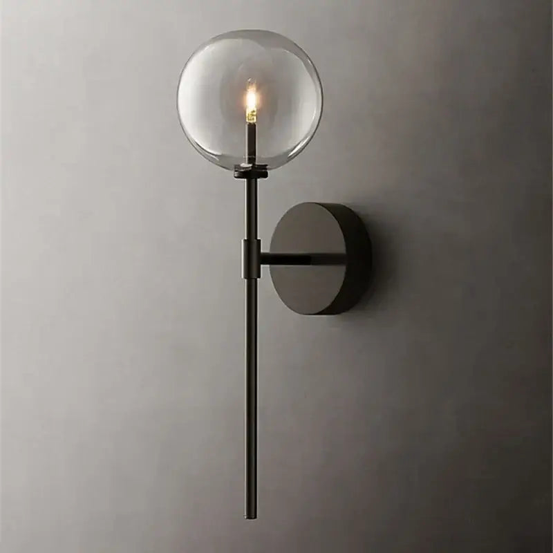 Modern black metal wall sconce with a clear glass ball and exposed filament bulb for retro living room lighting