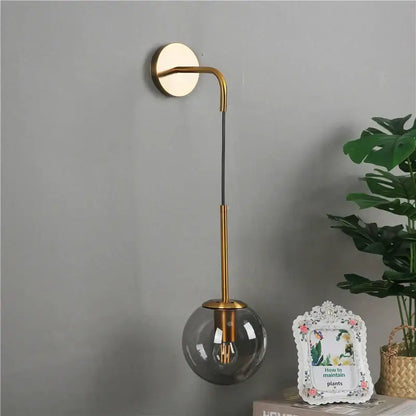 Retro gold glass ball wall lamp with gold-toned curved arm and smoked glass shade for bedroom decorbites glass ball sconce