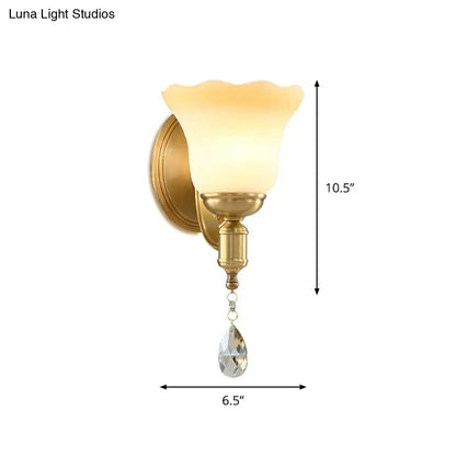 Retro gold wall lamp featuring a blossom opaque glass shade with a dangling teardrop crystal sconce for bedroom use