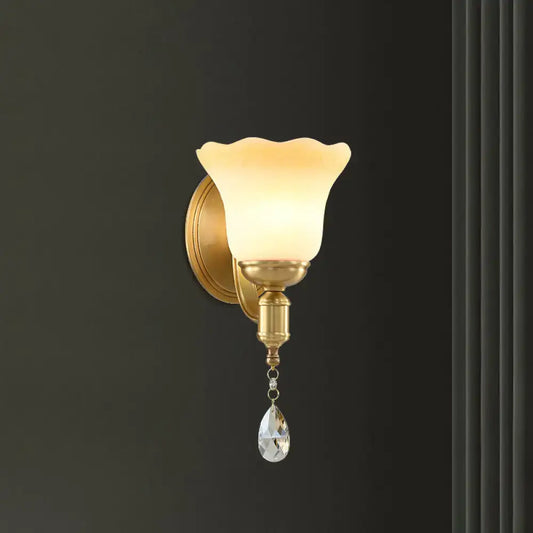 Gold-toned retro wall lamp with blossom opaque glass shade and crystal teardrop for elegant bedroom use