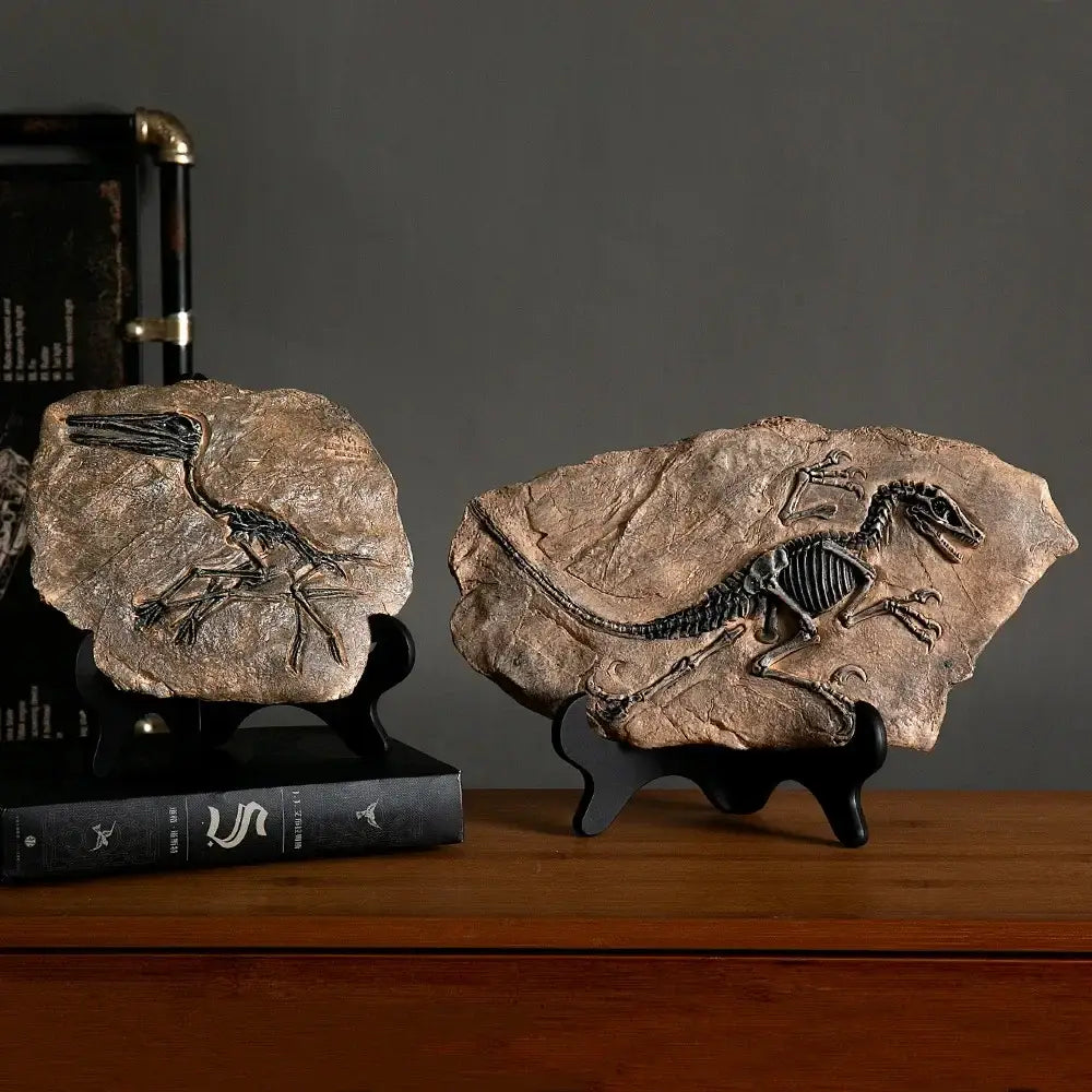 Two retro animal statue rock slabs with detailed black dinosaur fossil imprints on black stands for living room decor