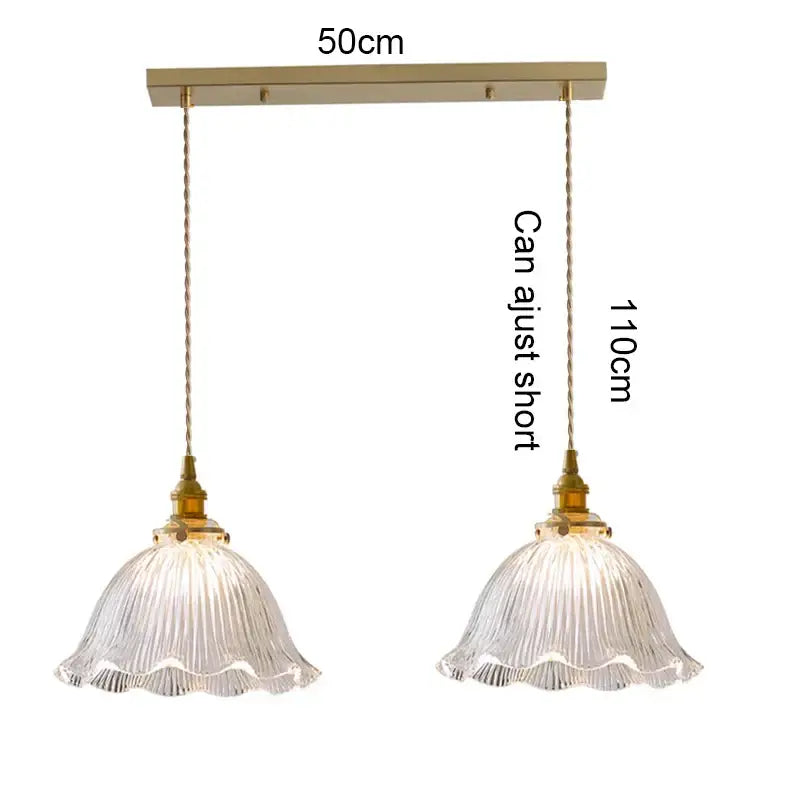 A pair of clear glass pendant lights with fluted ruffled shades brass hardware and wood accent for dining room use
