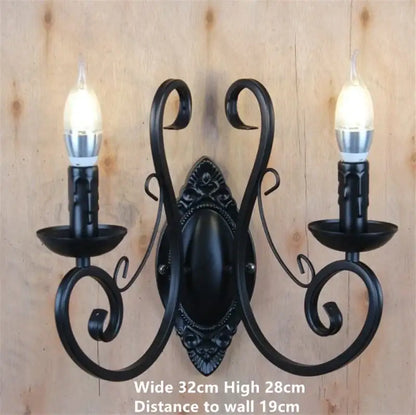 Black wrought iron two-light wall sconce with ornate scrollwork and candle-style bulbs for living room decorbites black wrought