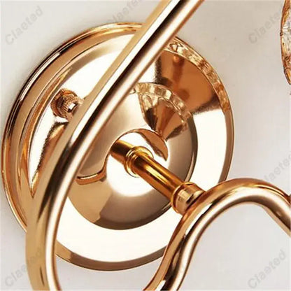 Gold-toned metal retro industrial wall lamp sconce with ornate curved arms and polished reflective surfaces for bedroom