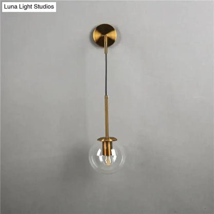 Brass-finished wall lamp with retro modern glass smoked globe and exposed filament bulb for bedroom lighting