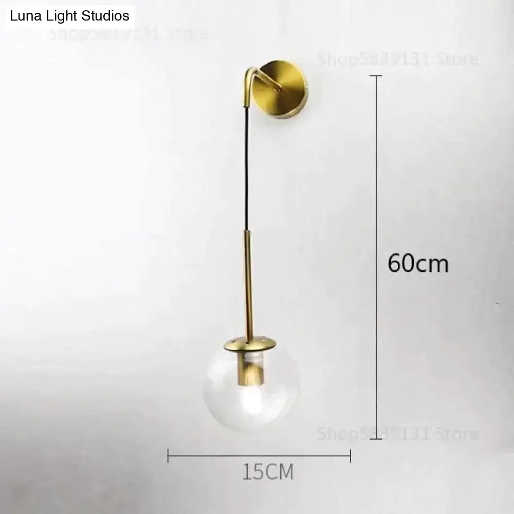 Gold-toned nordic retro modern wall lamps with clear glass smoked globe and slender metal arm for bedroom lighting