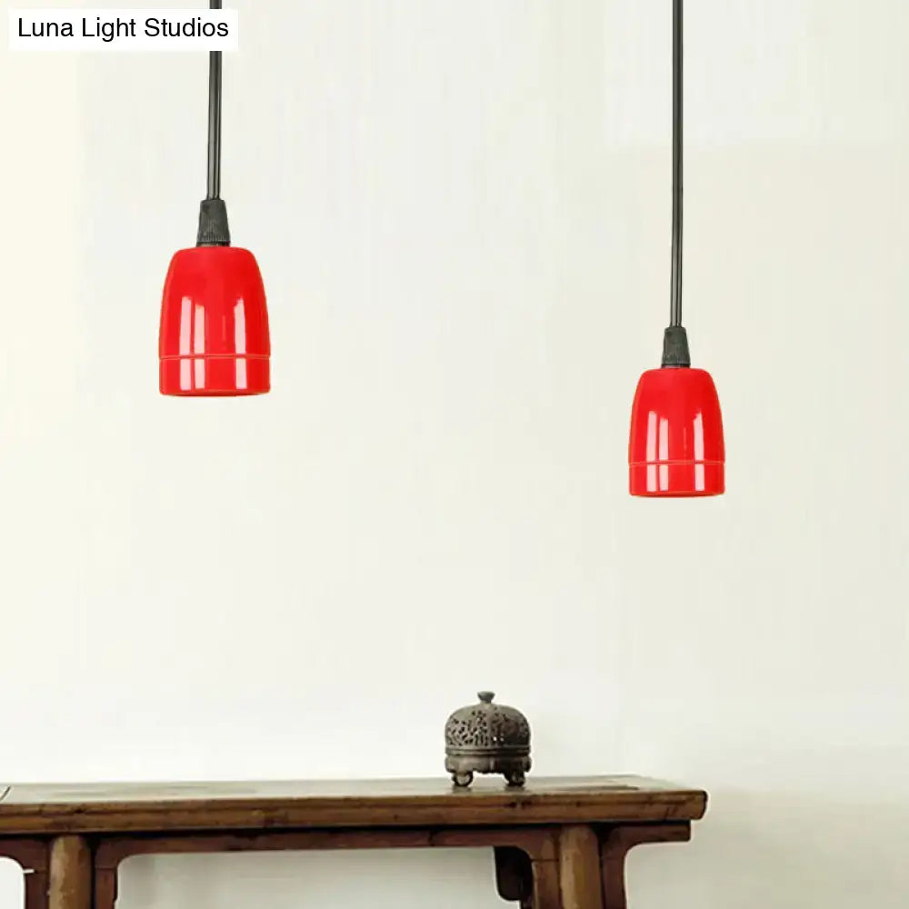 Two vibrant red ceramic pendant lights with black cords hang from the ceiling in a decorbites retro style fixture