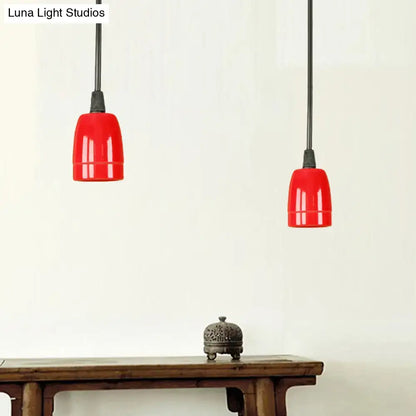 Two vibrant red ceramic pendant lights with black cords hang from the ceiling in a decorbites retro style fixture