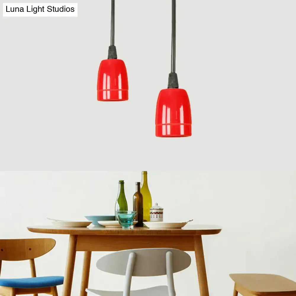 Two vibrant red ceramic pendant lights with black cords hang above a wooden table in a decorbites retro style fixture