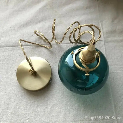 Retro teal and brass glass pendant chandelier featuring a ceramic globe light with brass hardware and twisted cord