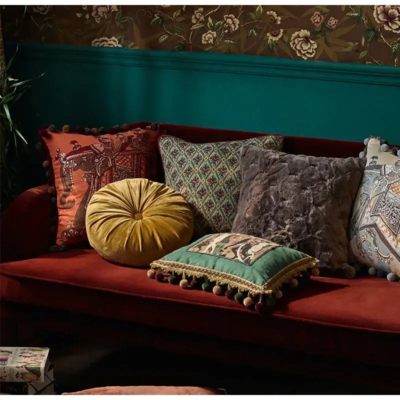 A plush mustard-yellow velvet round pillow with tufted center on red sofa complements decorbites american luxe cushion covers