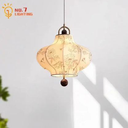 A cream fabric retro pendant light with intricate floral embroidery and dark wooden base by decorbites wabi-sabi