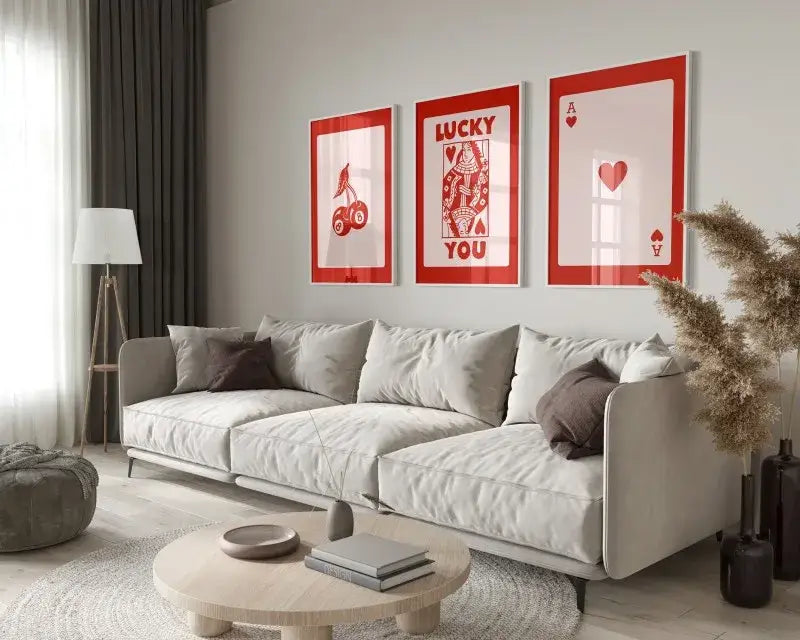 Three framed red and white queen of hearts themed retro wall art posters hanging above a light gray sofa