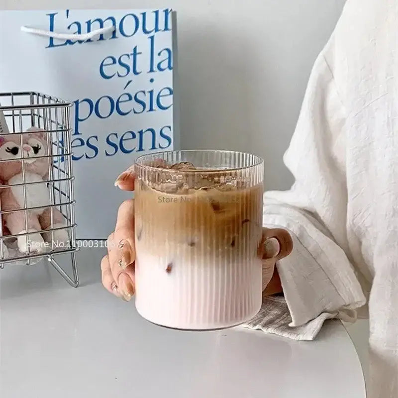 Clear glass coffee ribbed tumbler set with frosted base containing gradient iced coffee by decorbites clear glass