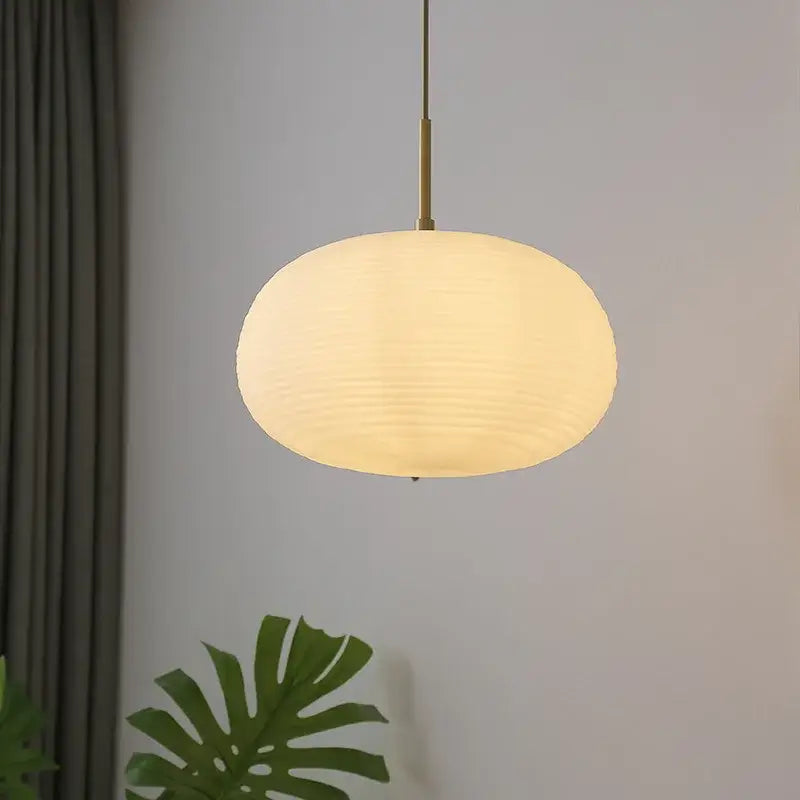 Warm softly glowing oval pendant chandelier with textured paper shade and brass rod ideal for dining room lighting