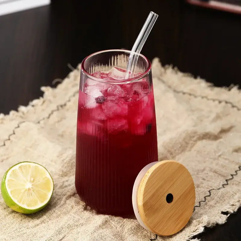 A tall ribbed glass cup from a glass cup set filled with vibrant red beverage and ice cubes for kitchen dining