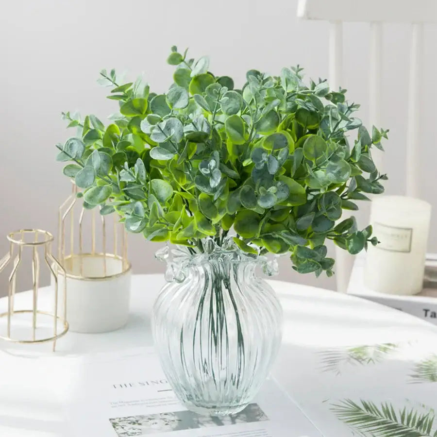 A clear ribbed glass eucalyptus leaves vase holding artificial vibrant green eucalyptus leaves for lavender decor