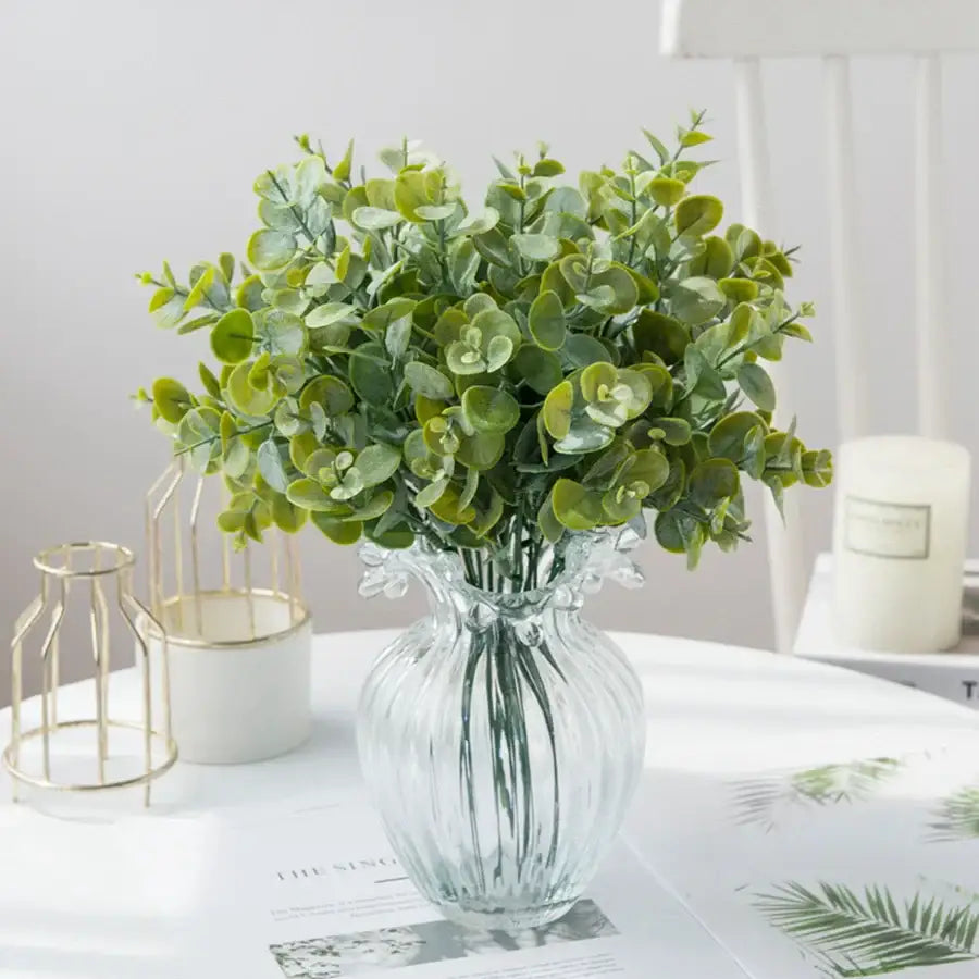 A clear ribbed glass eucalyptus leaves vase with round green artificial eucalyptus leaves for lavender living room decor