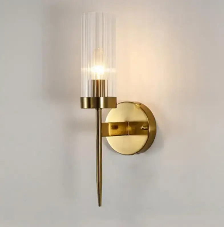 Gold-toned wall lights with a clear vertically ribbed glass shade and slender metallic stem by decorbites gold led for bedroom
