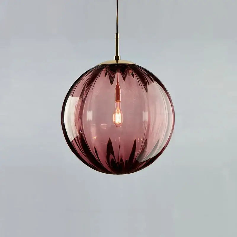 A spherical amethyst glass globe pendant light with brass fixture and exposed bulb for dining room iron finish