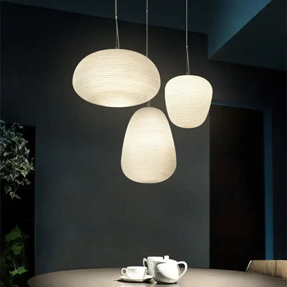 Three off-white ribbed glass cocoon pendant lights with concentric ridges hang from thin cords for dining room decorbites glass cocoon pendant