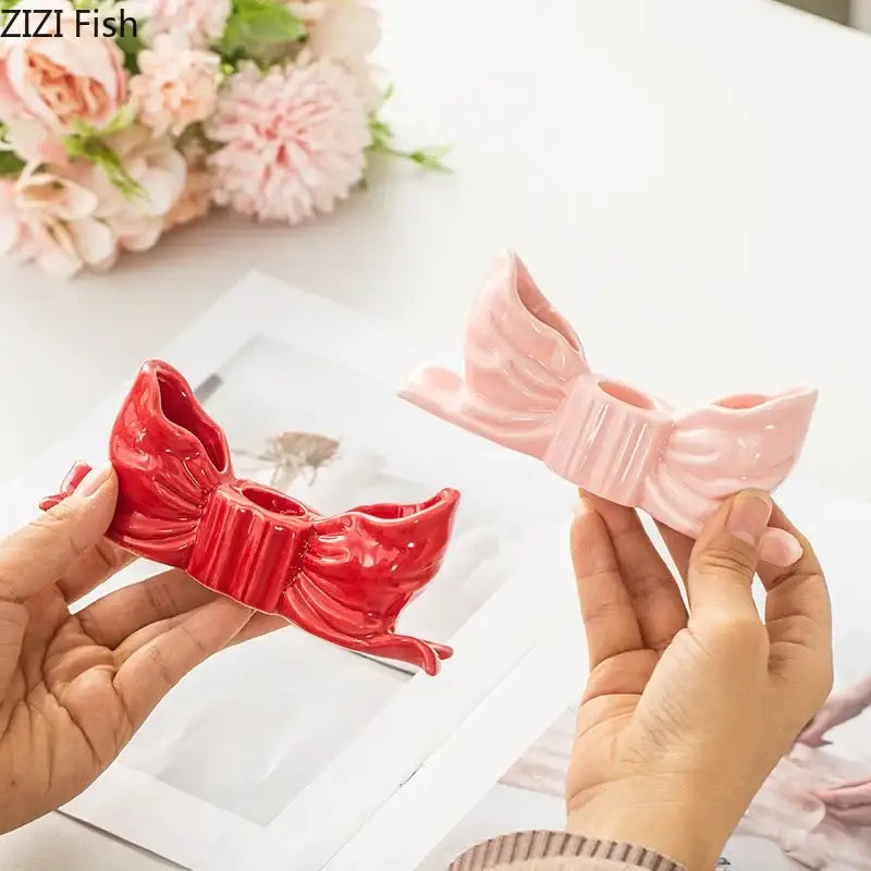 Two glossy ceramic bowknot candle holders in vibrant red and soft pink for bedroom desk decor by decorbites