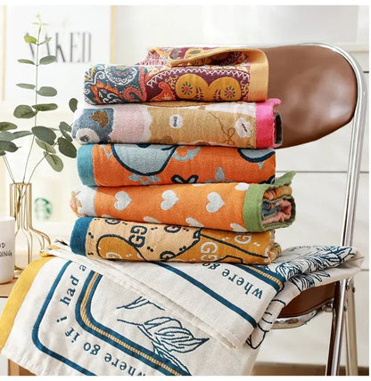 Stack of colorful patterned cotton bath towels with embroidered romantic beige and black floral designs for bathroom decor