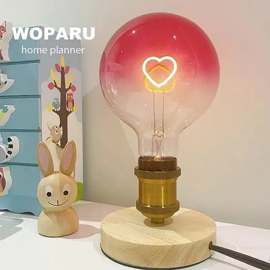 Romantic gradient pink led filament heart light bulb with a red-to-clear glass bulb on brass and wood stand by decorbites