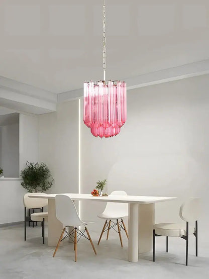 A vibrant rose gold pink glass chandelier with cascading cylindrical shades hangs above the dining table