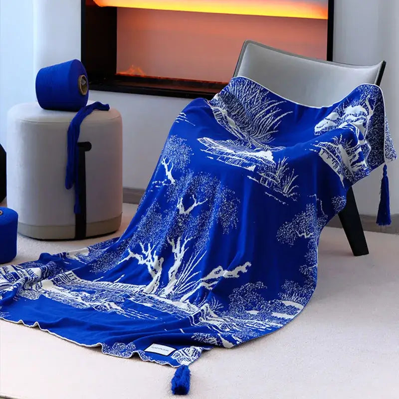 Royal blue and white knitted sofa blanket in silk with intricate landscape pattern and tassels for living room use