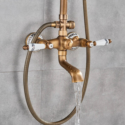 Antique brass shower faucet with white ceramic handles featuring blue floral patterns and a flexible hose for bathroom use