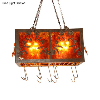 Rectangular island light with amber leaf-patterned glass panels and dark metal frame for rustic dining room lighting