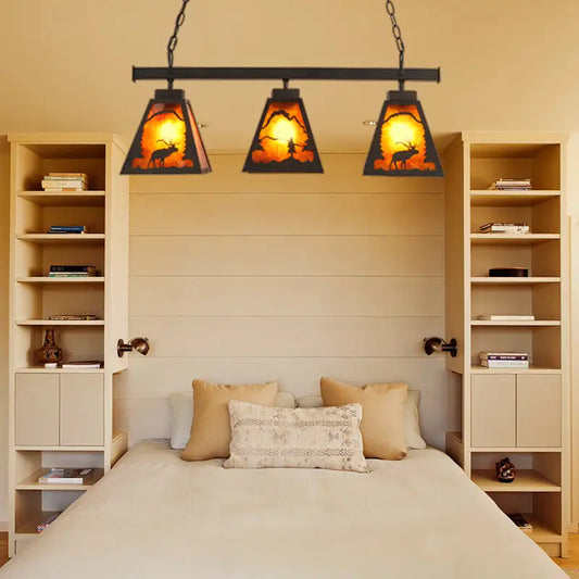 Rustic black metal pendant light with three amber backlit triangular glass shades and deer silhouette scene for dining room