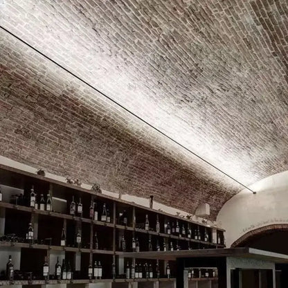 Rustic black and white steel wall lamp strip mounted on an arched ceiling of weathered earthy brick wall lamp strip