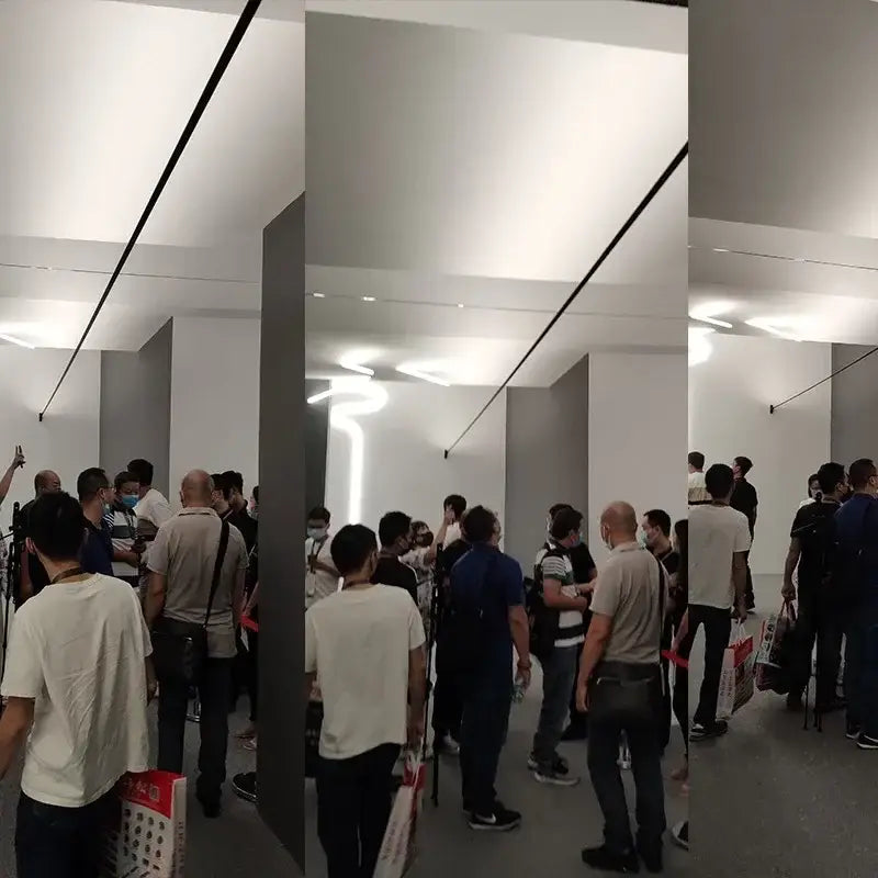 Crowd inside an apple store highlighting rustic black and white steel wall lamp strip for aisle brick decor