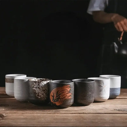 A rustic coarse ceramic tea cup set with unique textured glazes and hand-painted designs in earthy tones