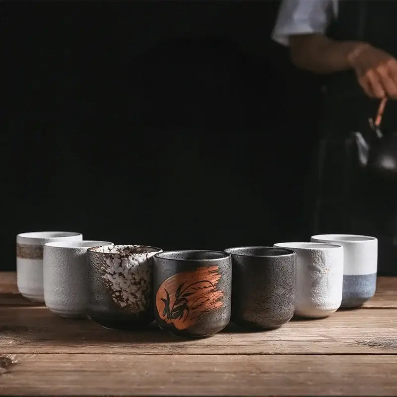 A rustic coarse ceramic tea cup set with unique textured glazes and hand-painted designs in earthy tones