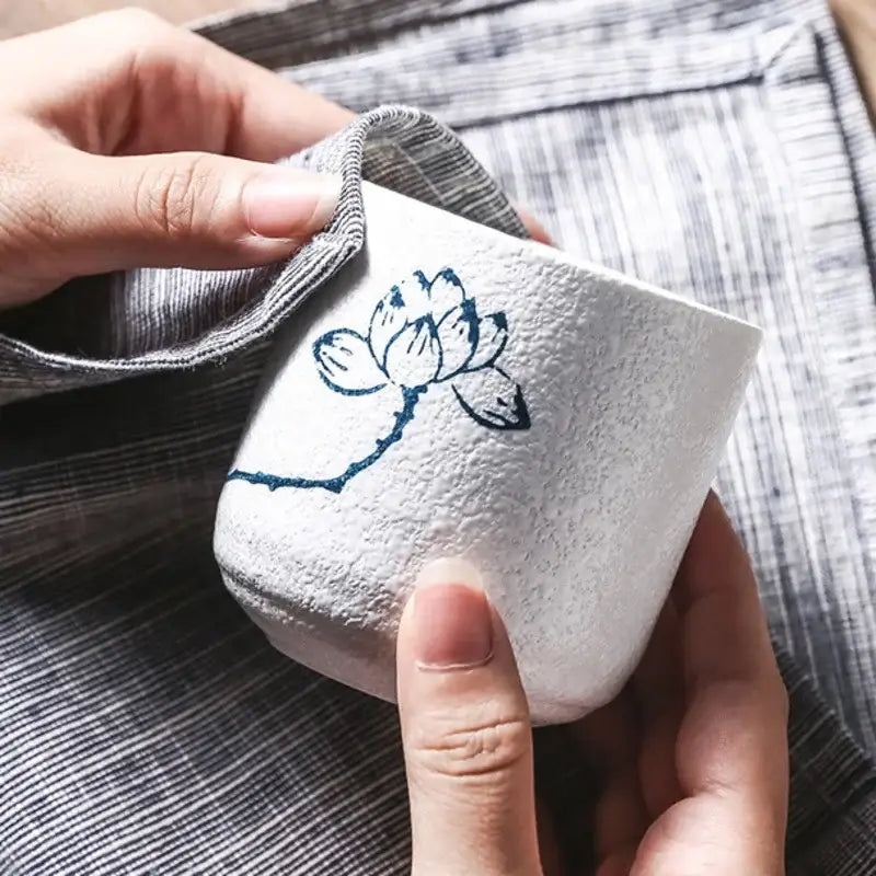 White coarse ceramic tea cup with textured surface and blue lotus design from decorbites rustic hand painted set