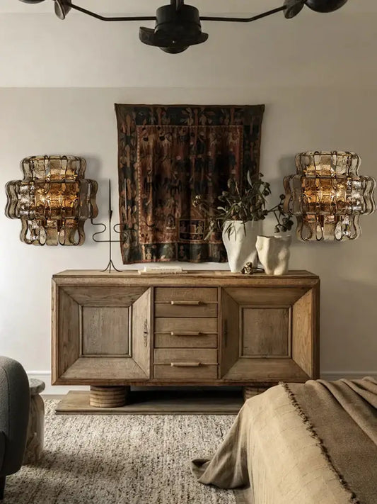 Rustic dark brown glass wall sconce lamps beside a weathered wooden sideboard with drawers and cylindrical legs