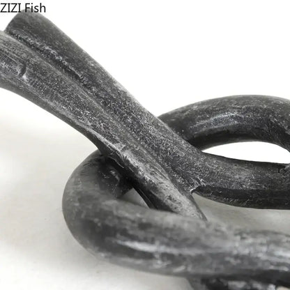 Rustic dark metal geometric knot resin sculpture featuring a textured hand-forged chain for living room decorbites geometric knot decor