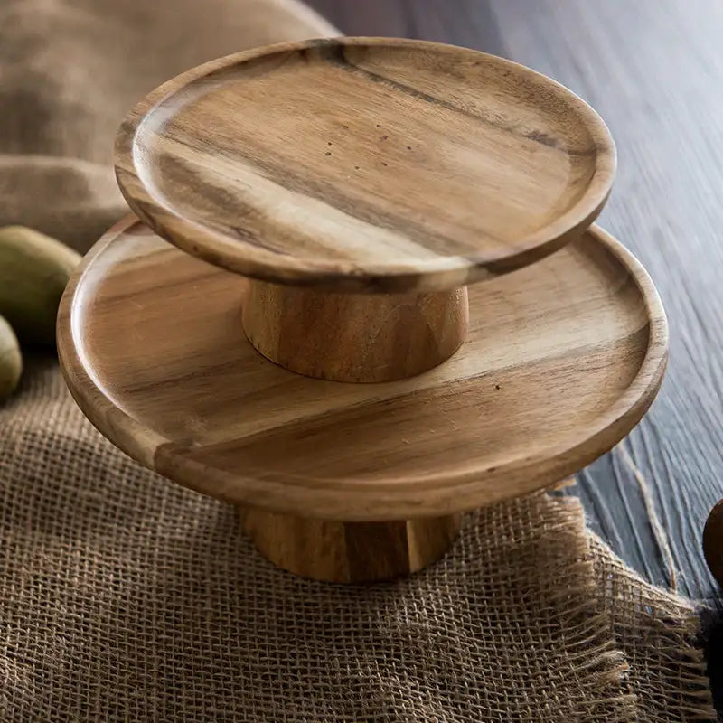 Two-tiered decorbites elevated wooden cake stand with natural light brown finish and visible wood grain for serving