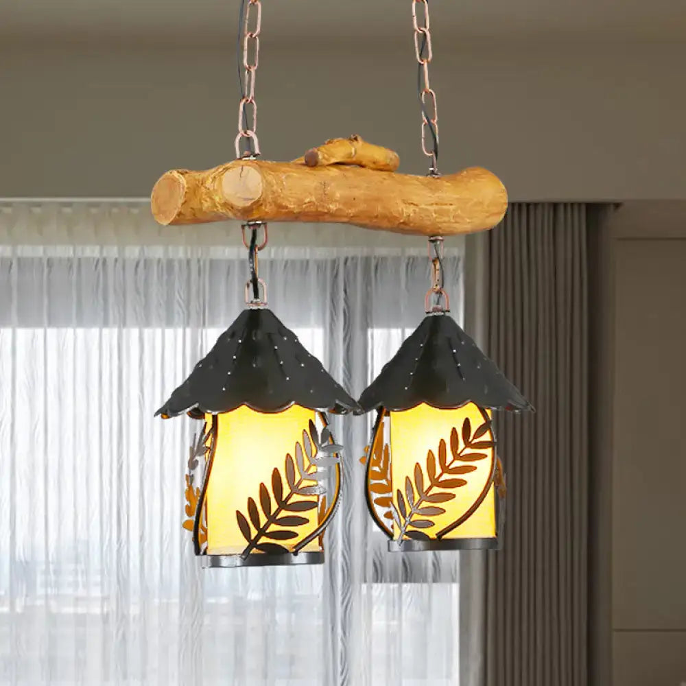 Rustic wooden branch pendant light with two black leaf-patterned glass shades and fabric clear glass shade emitting warm glow