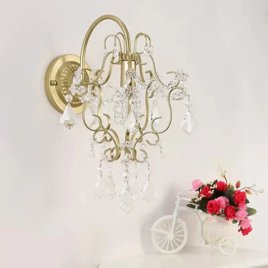 Rustic gold crystal wall mount lamp with gold-toned ornate design and dangling clear crystal droplets for bedroom use