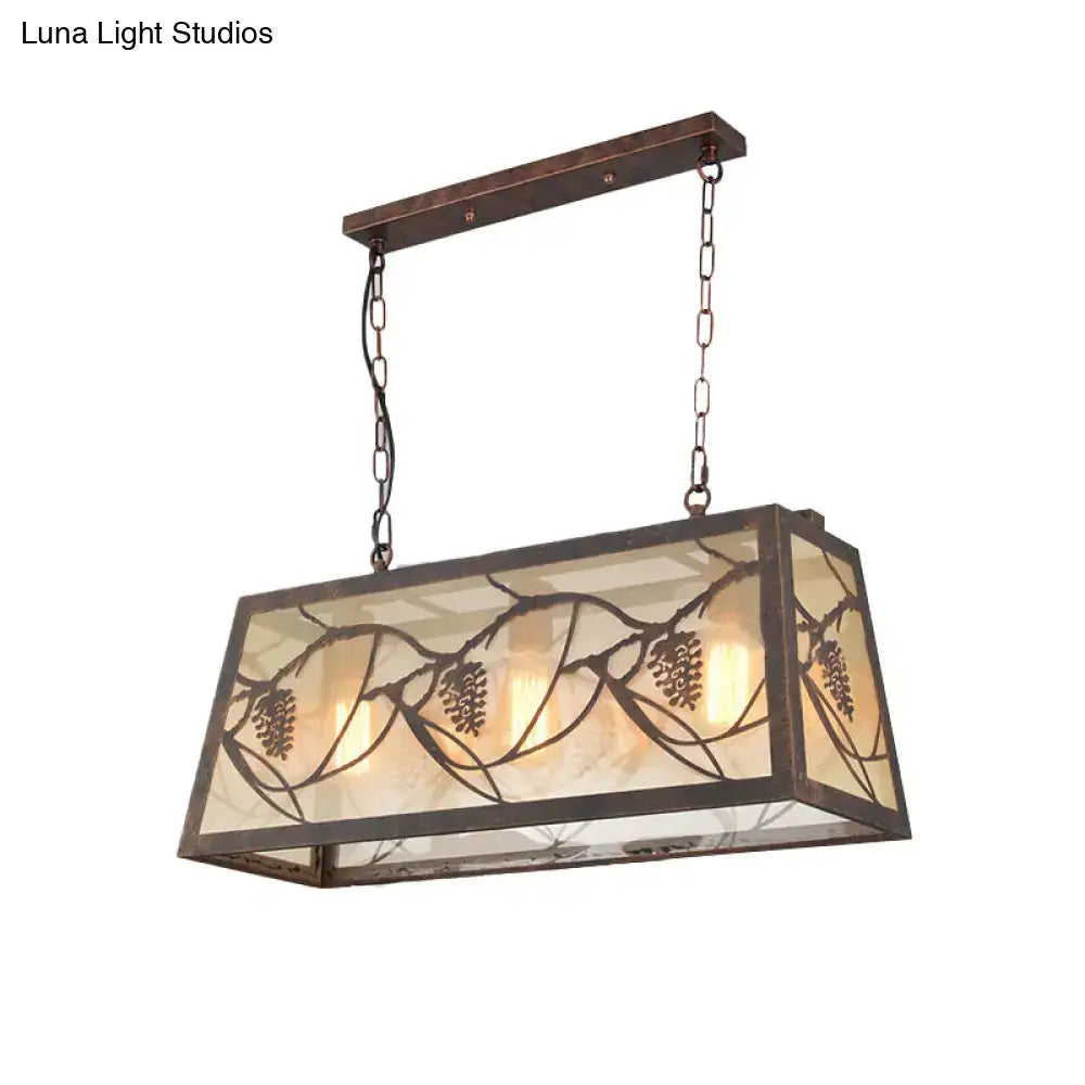Rectangular island light fixture with bronze metal frame and amber stained glass panels featuring pinecone motifs